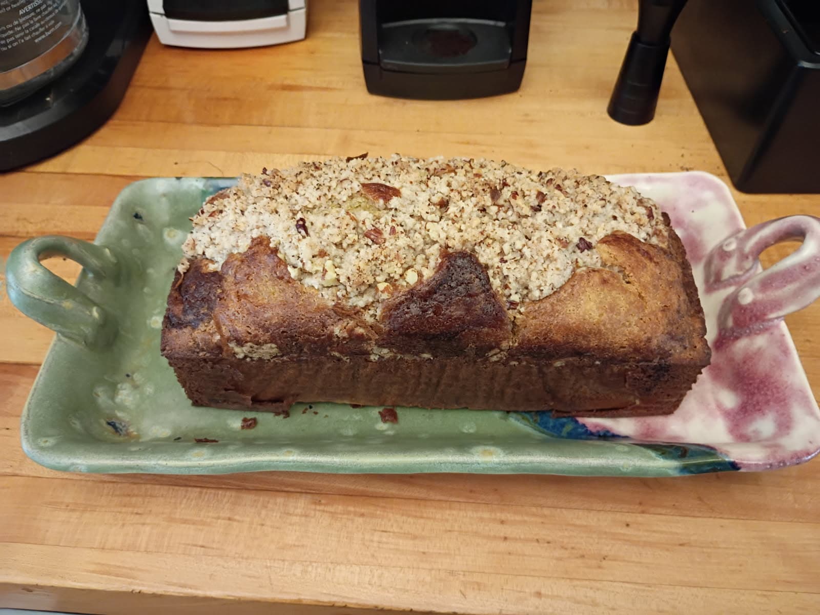 A freshly baked loaf of bread topped with a crumbly, golden crust on a decorative platter.